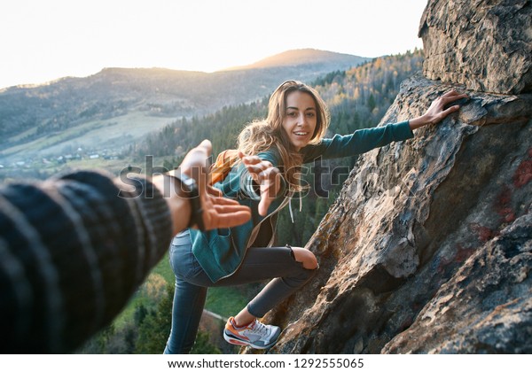 first person view of a\
young pretty woman hiker climbed on the cliff, looking confused and\
getting help