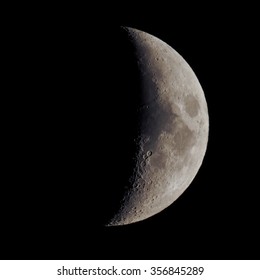 First quarter moon over dark black sky seen with a telescope from northern emisphere at night