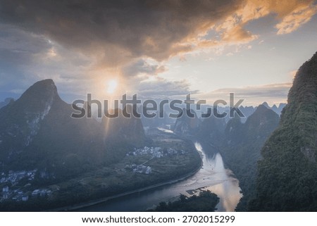 First rays of light through the clouds in Xianggong hill landscape of Guilin, Li River and Karst mountains. Xingping, Yangshuo County, Guangxi Province, China.