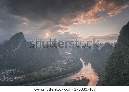 First rays of light through the clouds in Xianggong hill landscape of Guilin, Li River and Karst mountains. Xingping, Yangshuo County, Guangxi Province, China.