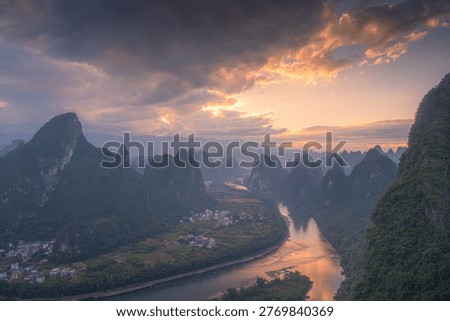First rays of light through the clouds in Xianggong hill landscape of Guilin, Li River and Karst mountains. Xingping, Yangshuo County, Guangxi Province, China.