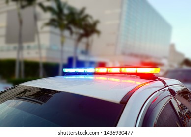 First responder police car cruiser, flashing a full array of blue and red tactical lights against a bokeh roadblock and checkpoint looking for drivers under the influence of liquors or illegal drugs - Shutterstock ID 1436930477