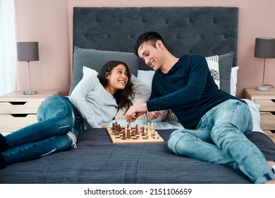 First rule of surviving lockdown Have fun. Shot of a young couple playing a game of chess at home.