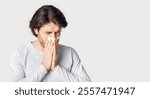 First signs of disease. Guy blows his nose in napkin isolated on gray background, studio shot