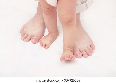 First Steps Of Baby Learning To Walk With Help Of Mothers And Fathers, New Family And Baby Protection Concept