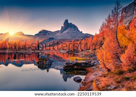 First sunlight glowing hills of Federa lake. Spectacular sunrise in Dolomite Alps with orange larch trees on the shore. Colorful morning scene of Italy, Europe. Beauty of nature concept background.
