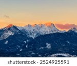 First sunrise sunlight on majestic snow-capped mountain summit Mittagskogel in Karawanks seen from Rosental, Carinthia, Austria. Alpine winter wonderland landscape at night in serene Austrian Alps