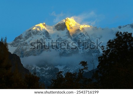 First sun's rays touching the summit of Ultar Peak (7388 m, also Ultar Sar, Bojohagur Duanasir II) - the southeasternmost major peak of the Batura Muztagh, a subrange of the Karakoram range, Pakistan
