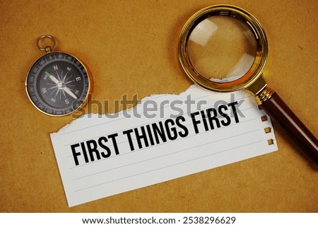 First Things First text on paper torn with compass and magnifying glass on paper craft background