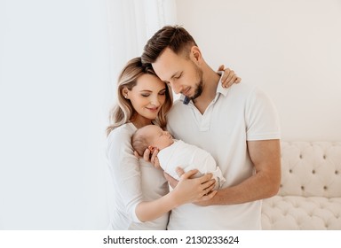 First time parents holding their newborn baby girl, smiling. - Powered by Shutterstock