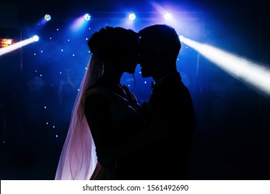 The first wedding dance of the newlyweds.Silhouettes of loving couple in the dark