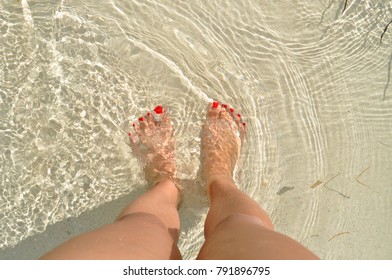 First-person point of view looking down on saltwater and sand on my feet