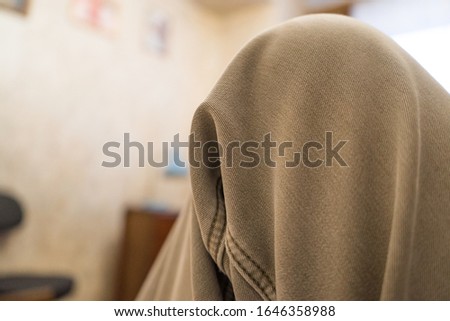 first-person view, a knee dressed in marsh-colored trousers, a wall of a house pasted with wallpaper, paintings on the wall, a window. Person on the bed at home and expect something to happen.