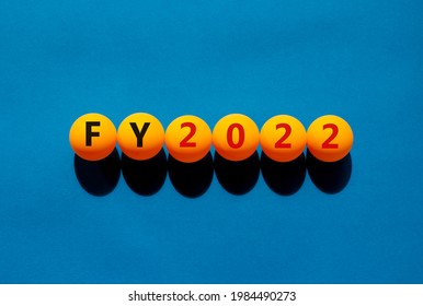 Fiscal year 2022 and business symbol. The concept word 'FY, fiscal year 2022' on orange table tennis balls on a beautiful blue background. Business and FY, fiscal year 2022 concept.