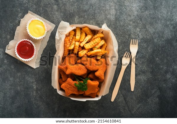 Fish and Chips british fast food. Fish Sticks with\
french fries set on takeaway paper plate on dark old concrete\
background. Traditional British authentic street food or takeaway\
food. Mock up.