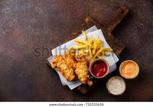 Fish and Chips british fast\
food with three popular sauce for choice on brown background copy\
space