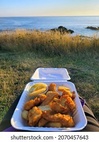 Fish And Chips With Lemon Inside White Takeout Box Overlooking Oregon Ocean At Sunset