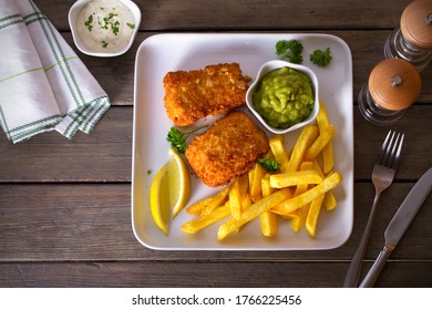 Fish And Chips, Mushy Peas And Sauce On White Plate. Overhead Horizontal Image