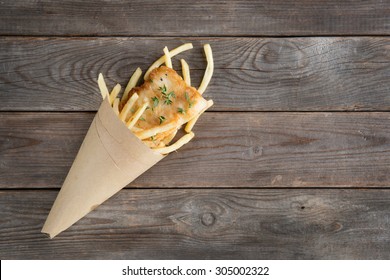 Fish And Chips. Overhead View Fried Fish Fillet With French Fries Wrapped By Paper Cone, On Wooden Background.