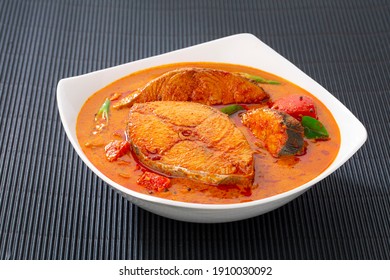 Fish curry_Seer fish curry ,traditional Indian fish curry ,kerala special dish using coconut ,arranged in a white bowl garnished with curry leaves  on black textured  background, isolated.