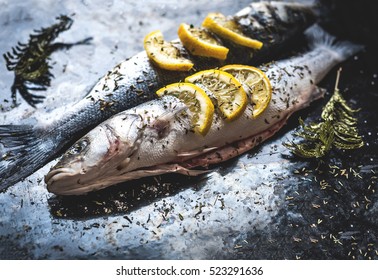 Fish Dish Cooking With Various Ingredients. Raw Sea Bass With Lemon, Garlic, Herbs And Spices On Cutting Board, Top View. Healthy Food Or Diet Nutrition Concept. 