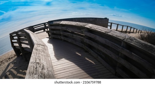 Fish eye lens landscape with the view of curved wooden deck, ocean, and the blue sky with clouds