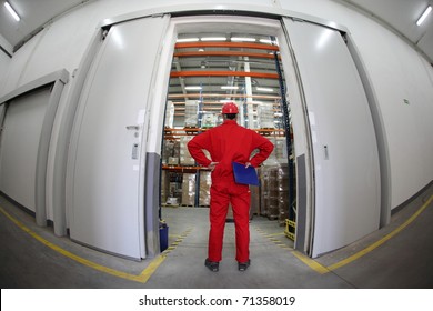 A fish eye view of a worker standing in the doorway of a modern industrial facility. - Powered by Shutterstock