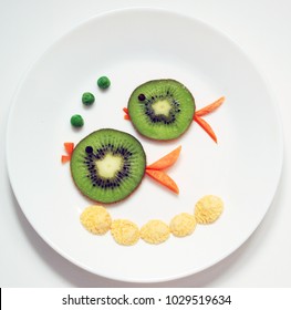 Fish Family. Parents And Children. Food Art From Fruit Kiwi. Healthy And Fun Food For Kids On White Plate, Top View.