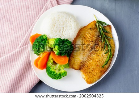 Fish fillet with rice and broccoli. White fish steak baked with vegetables and white rice.