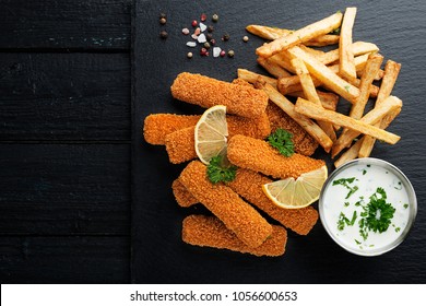 Fish Fingers And Fries With Sauce On Dark Background. Top View.