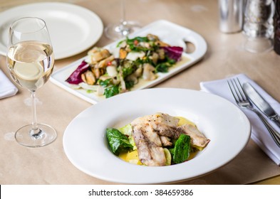 Fish Fried With Vegetables , Seafood Salad And White Wine - A Lovely Dinner For Two . Living Healthy Food . Close-up In White Plate On The Served Table.
