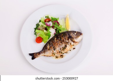 Fish Grill  Dish Baked Whole Grilled On A Plate With Vegetables And Lemon On Top For The Menu Isolated