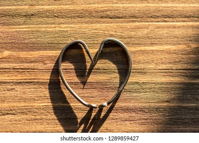 Fish Hook Heart On A Wooden Background.