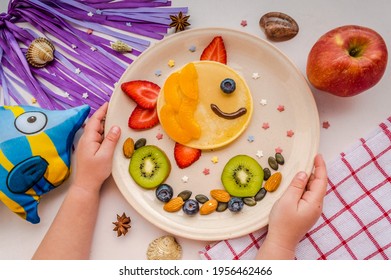 Fish Made Of Pancake With Strawberry And Fruit For Kids. Top View Of Kid Having Breakfast. Plate With Funny Pancake And Kid's Hands. Funny Breakfast Idea For Children.