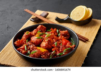 Fish Manchurian Dry Looks Like Schezwan Fish In Black Bowl At Dark Slate Background. Fish Manchurian - Is Indo Chinese Cuisine Dish With Deep Fried Salmon, Bell Peppers, Sauce And Onion.