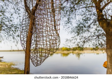 A Fish Net Hanging On The Tree Next To A  Lake