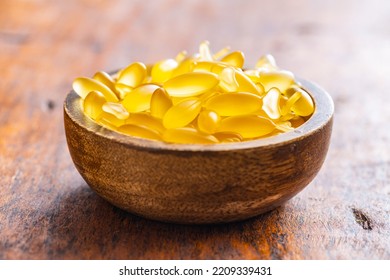 Fish Oil Capsules In Bowl. Yellow Omega 3 Pills On The Wooden Table.