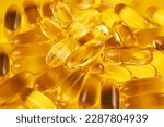 Fish oil capsules with omega 3 and vitamin D on yellow background.
