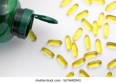 Fish Oil Capsules Pouring Out Of A Green Bottle Isolated On A White Background. Omega 3 Capsules.