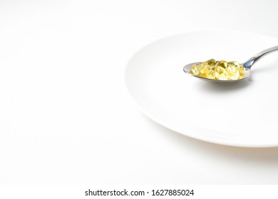 Fish Oil Capsules In The Spoon On A White Plate With Copy Space. Side View.