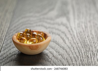 Fish Oil Capsules In Wood Bowl On Wooden Table