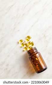 Fish oil capsules. Yellow omega 3 pills in glass bottle on the white table. Top view. - Shutterstock ID 2210063049
