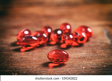 Fish Oil Gel Capsule, Red Color, Closeup, Blur Capsules Background On A Wooden Table