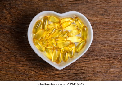 Fish Oil In Heart Shape Bowl On Wooden Board Background