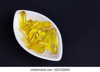 Fish Oil In White Bowl On Black Texture Background.