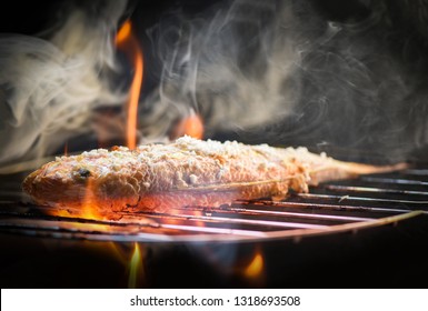Fish on grill / Close up of seafood grilled fish food with salt on the grill fire and smoke on dark background 