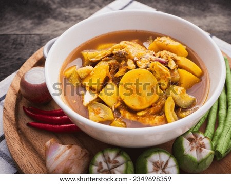Fish organs sour soup with vegetables in bowl on wooden table background. Traditional Thai southern food