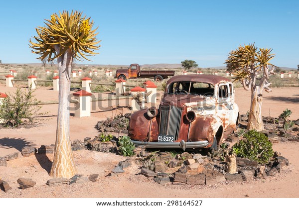 FISH RIVER CANYON, NAMIBIA - JUNE 17,\
2011: A rusted old car in a succulent garden between flowering\
quiver trees at a lodge near the Fish River\
Canyon