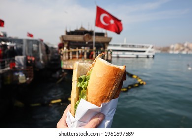 İstanbul fish sandwich, also known as Balık Ekmek which is the best street food in İstanbul, Eminönü, on background blurry ship and Turkish flag. - Shutterstock ID 1961697589