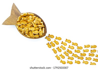 Fish Shaped Bowl Full Of Goldfish Crackers Chasing Little Fishes. Business Or Presentation Background Or Texture.